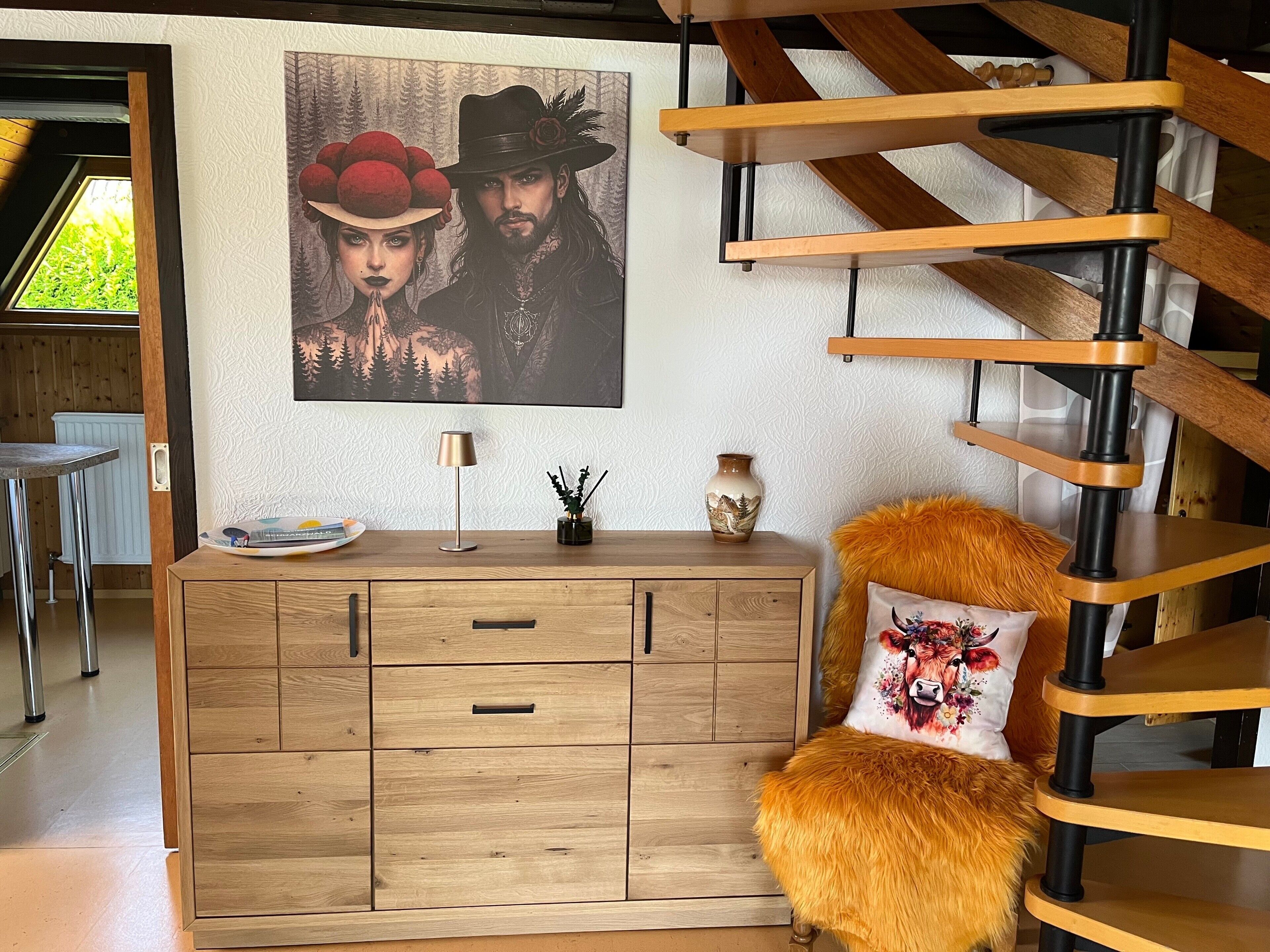 A room with a wooden staircase, a cabinet with drawers, a lamp, and a framed picture on the wall.