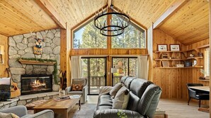 Interior acogedor de una cabaña con chimenea de piedra, sofá de cuero y paredes de madera.
