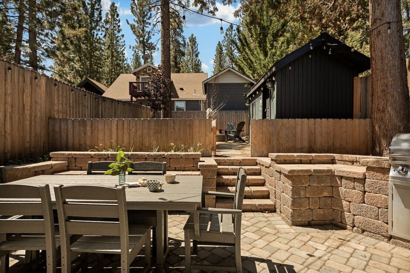 A patio area with a table and chairs, stone steps, and a barbecue grill.