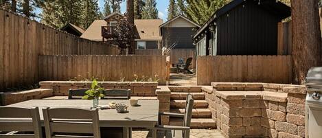A patio area with a table and chairs, stone steps, and a barbecue grill.