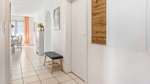 A hallway with a bench, a wooden panel wall, and a door.