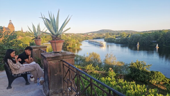 A river with boats, a bridge, and a cityscape with greenery and buildings in the background.