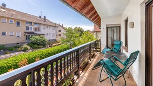 A balcony with a wooden railing, two green chairs, and a table.