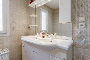 A bathroom with a double sink, a mirror, a white cabinet, and a tiled wall. - Villa 'L'Angloise' with Private Pool, Wi-Fi and Air Conditioning (Les Angles)
