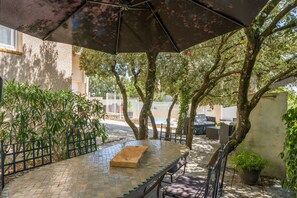An outdoor patio with a tiled table, benches, and a large umbrella. - Villa 'L'Angloise' with Private Pool, Wi-Fi and Air Conditioning (Les Angles)