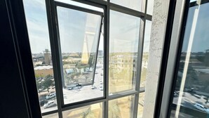 Vista a través de una ventana con cielo despejado, una grúa de construcción y edificios a lo lejos.