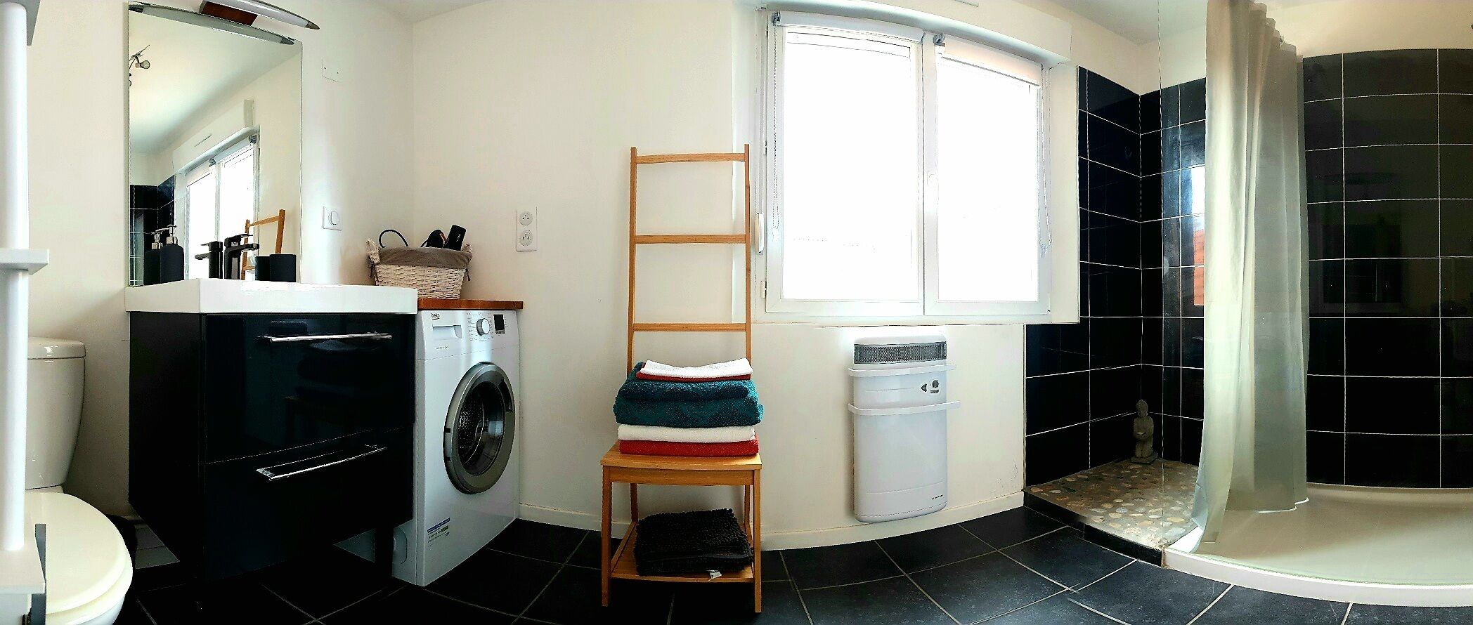 Une petite salle de bain équipée d’un lave-linge, d’un étendoir, d’une petite fenêtre, d’un espace douche et de toilettes.