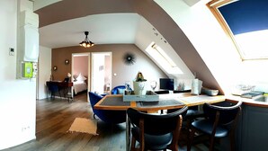 A modern kitchen with a dining area, a visible refrigerator, and a skylight. - EPERNEVASION: a cozy, air-conditioned apartment right in the heart of downtown Epernay. (Épernay)