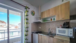 Eine Küche mit Holzausstattung, einer Mikrowelle, einem Spülbecken und einem Fenster mit Blick auf Gebäude.