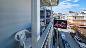 Ein Balkon mit dem Schild 'Villa Ana', einem weißen Plastikstuhl und Blick auf die Straße darunter.