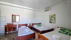 Ein Hotelzimmer mit zwei Einzelbetten, einem Holztisch, einem Stuhl, einem Spiegel und einer Klimaanlage.
