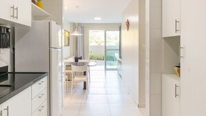 A modern kitchen with white cabinetry, a black countertop, and a coffee machine. - Aquarius Residence (Ipojuca)