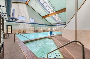 Ein Hallenbad mit klaren Glasdecken, einem gefliesten Boden und einer kleinen Whirlwanne.