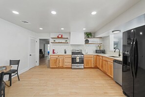 Eine moderne Küche mit Holzschränken, einem Edelstahlkühlschrank und einer Mikrowelle.