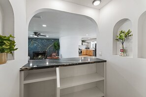 Ein modernes Interieur mit einer Marmarbeplatte, weißen Wänden und einer Küche im Hintergrund.