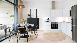 Et moderne køkken med hvide skabe, en sort bordplade og et rustfrit stål køleskab.