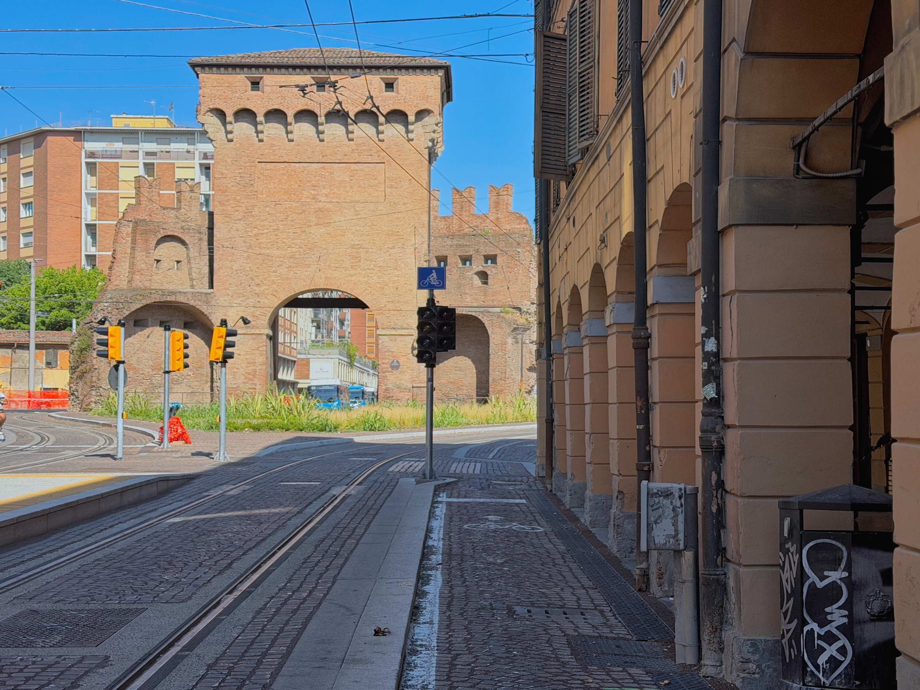 En gata med ett historiskt torn av tegel, spår för spårvagnar och ett övergångsställe för fotgängare.