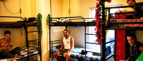 A dormitory room with bunk beds, a window, and a red cabinet.