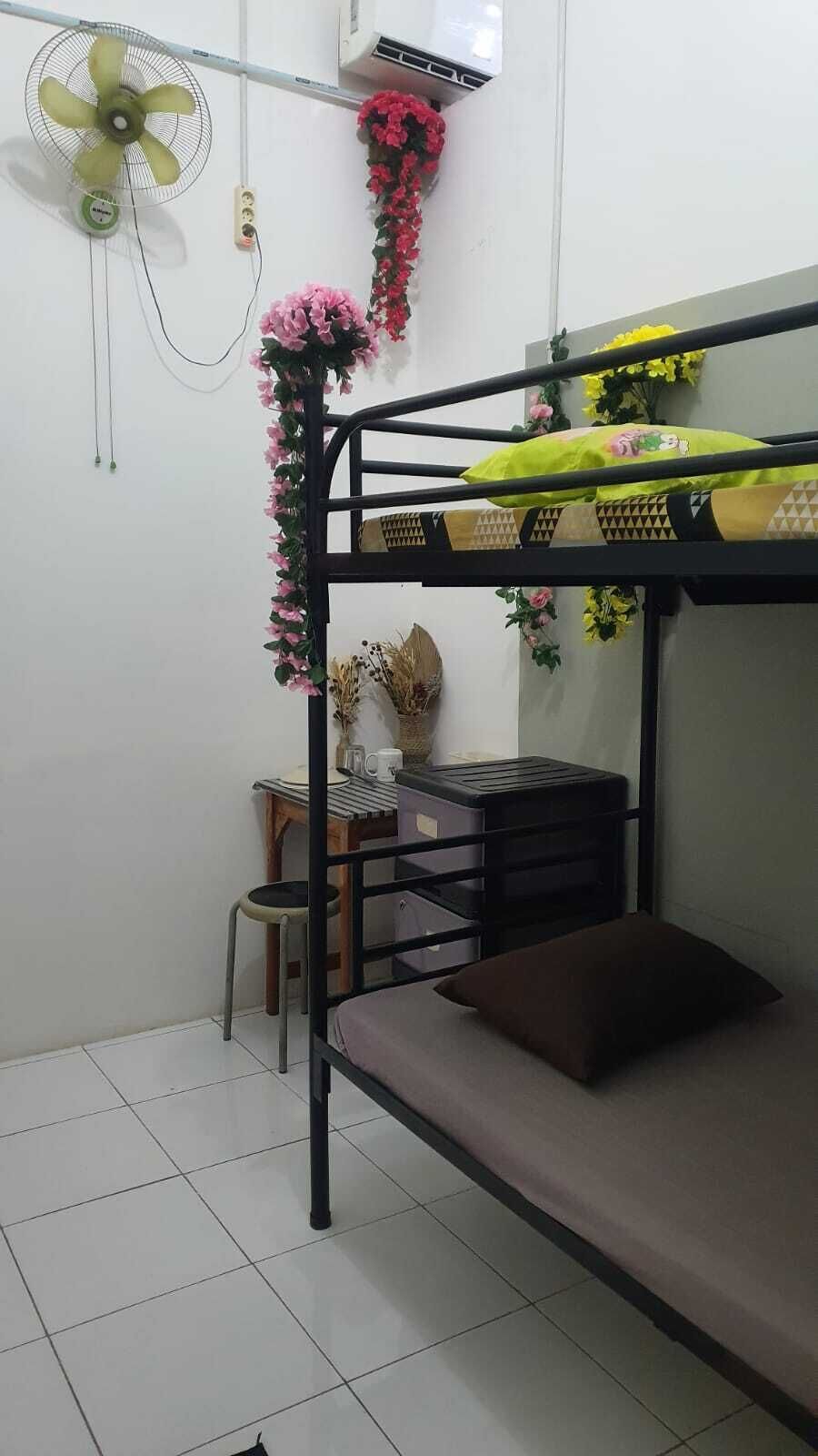 A bunk bed room with a desk, chair, and a fan.