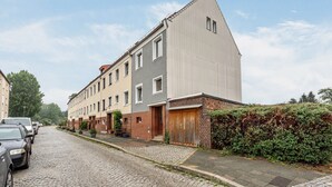 A residential street with a row of townhouses, a cobblestone road, parked cars, and a hedge on the right. - Room 'Ferienzimmer Nala und Loft' for Families and Holiday Guests (Görlitz)