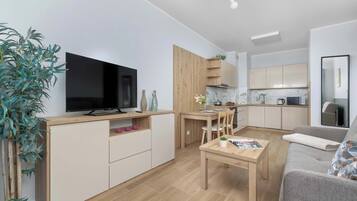Eine moderne Wohnung mit Fernseher, Küchenzeile, Essbereich und einer Sitzecke.