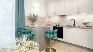 A modern kitchen with white cabinets, a central island, and teal bar stools.
