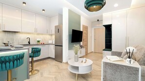 A modern kitchen with a built-in oven, a dining area with a round table, and a living room with a sofa.