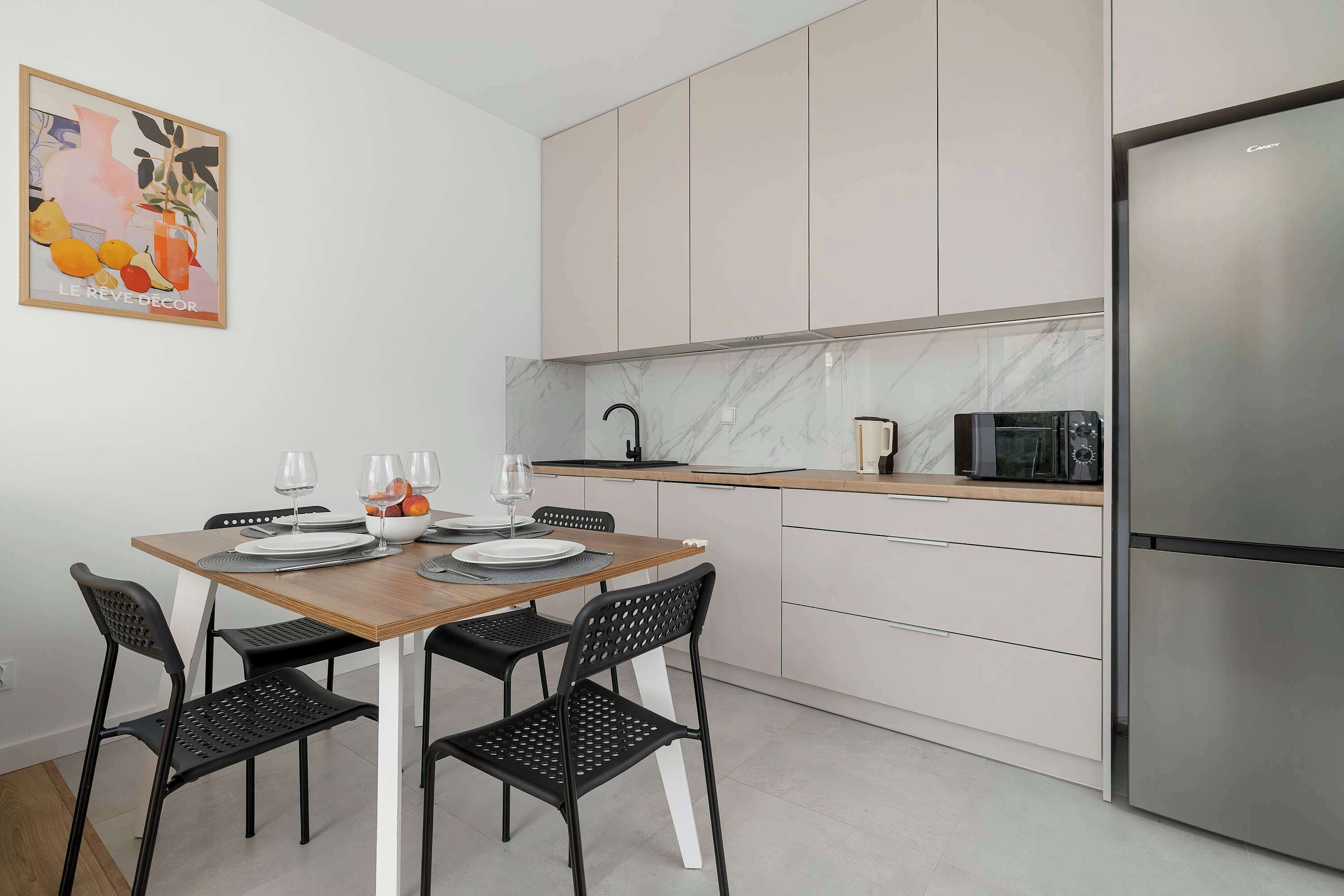 Una cocina moderna con una mesa de comedor para dos personas, un refrigerador y un microondas.
