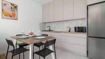 Una cocina moderna con una mesa de comedor para dos personas, un refrigerador y un microondas.