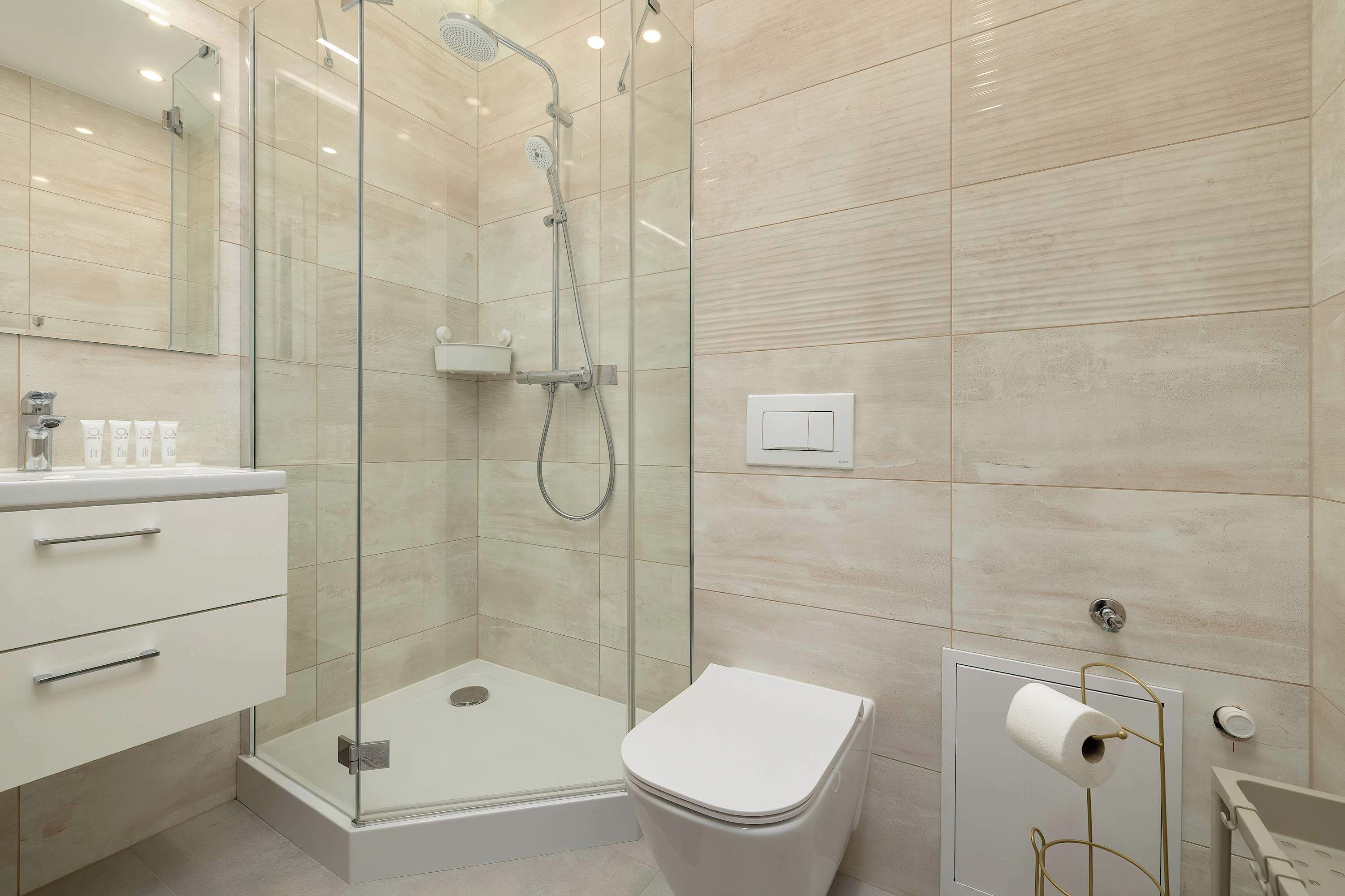 A modern bathroom with a glass-enclosed shower, a toilet, and a sink with a mirror.