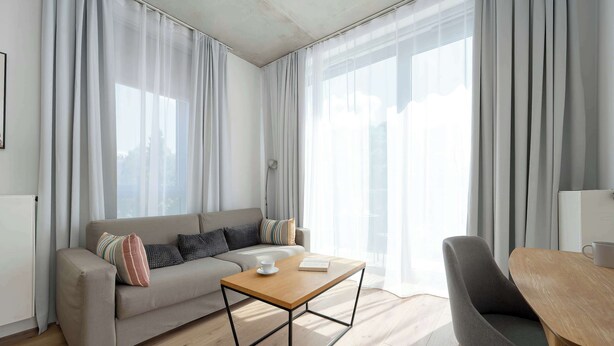 A modern living room with a sofa, a coffee table, and a dining table. - Modern Apartment in Center | Air Conditioning | Desk (Wrocław)