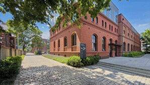 A red brick building with arched windows, a cobblestone pathway, and a signpost. - Modern Apartment in Center | Air Conditioning | Desk (Wrocław)