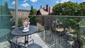 A balcony with a table and chairs, a vase with flowers, and a view of buildings and trees. - Modern Apartment in Center | Air Conditioning | Desk (Wrocław)
