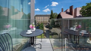 A balcony with a glass railing, a round table with chairs, and a vase of flowers. - Modern Apartment in Center | Air Conditioning | Desk (Wrocław)