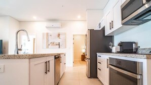 Een moderne keuken met roestvrijstalen apparatuur, witte kastjes en een granieten aanrecht.
