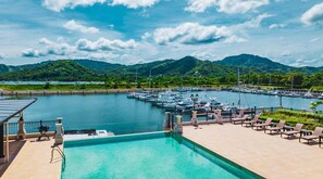 A marina with boats, a swimming pool, and a mountainous backdrop. - Marina View 2 Bedroom (Playa Flamingo)