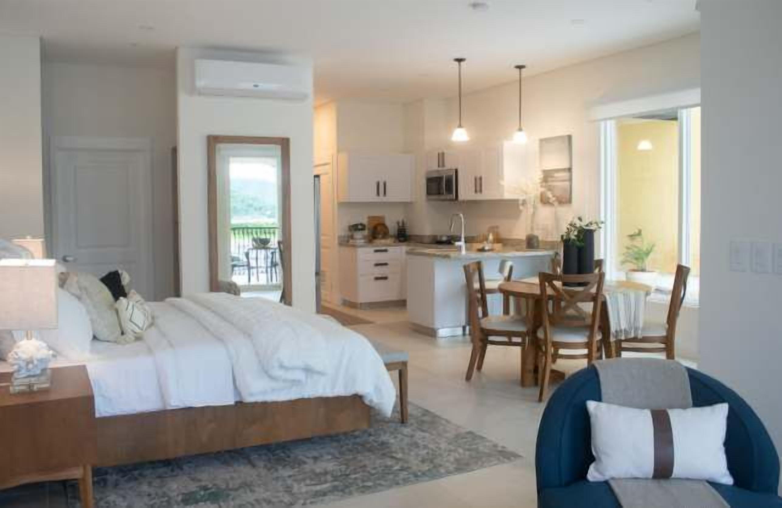 Une chambre avec un lit, une table de chevet et une vue sur la cuisine et le balcon.