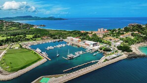 An aerial view of a marina with boats, a golf course, and buildings. - Flamingo View Studio (Playa Flamingo)