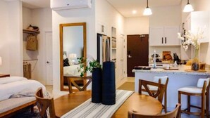 A modern hotel room with a bed, a dining table, chairs, a kitchen area, and a mirror. - Flamingo View Studio (Playa Flamingo)