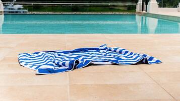 A poolside area with a tiled floor and a blue and white striped towel laid out.