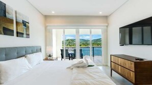 A bedroom with a bed, a TV, a wooden cabinet, and a balcony with a view. - Marina View 2 Bedroom Suite (Playa Flamingo)