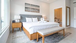 Une chambre moderne avec un grand lit, des tables de chevet, un banc et une vue sur la salle de bain.