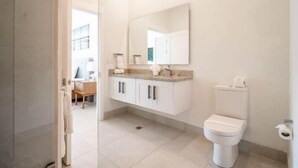 Une salle de bain avec des toilettes, un lavabo avec un miroir et des placards.