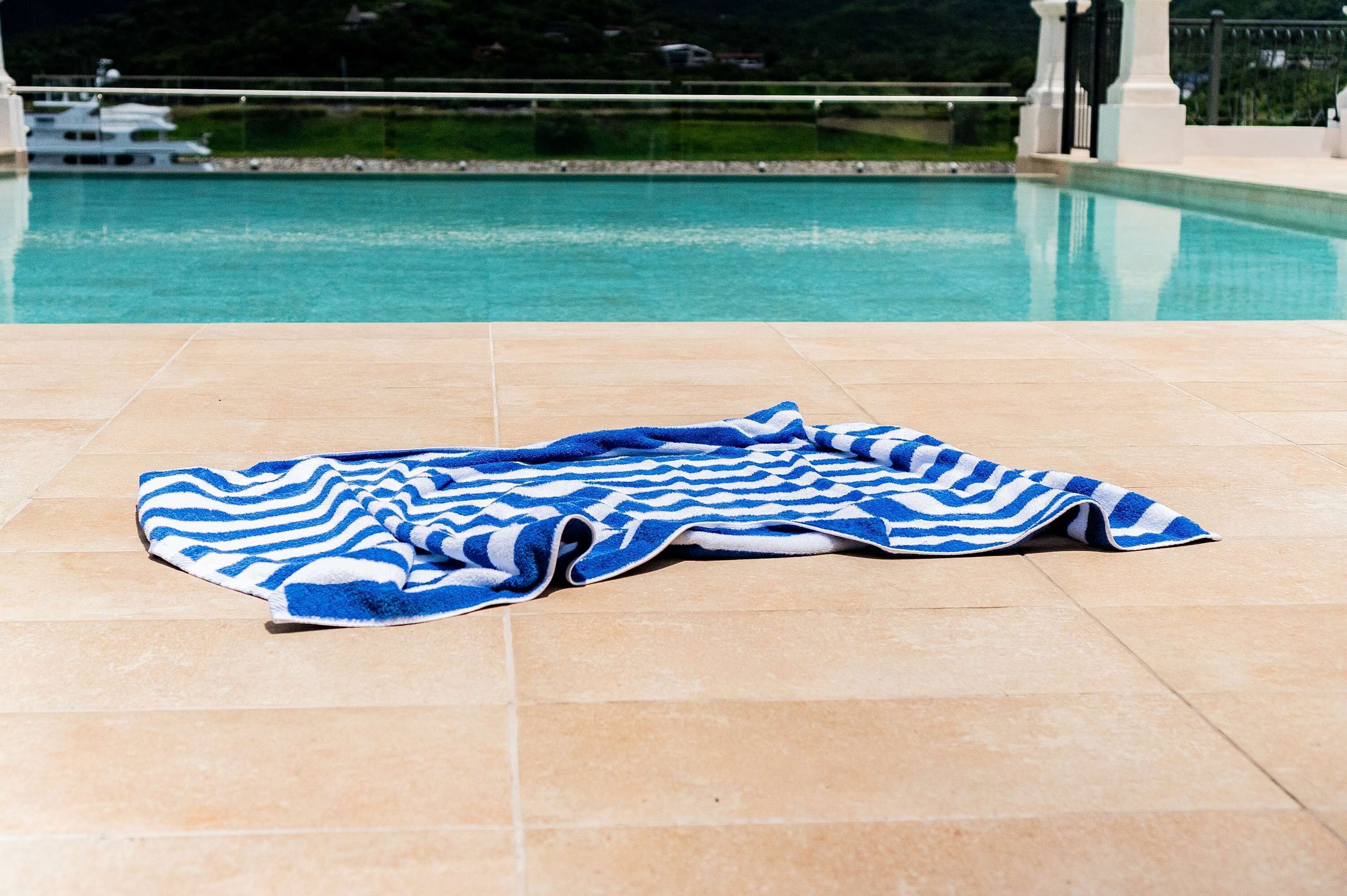 Ein Poolbereich mit gefliestem Boden und einem blau-weiß gestreiften Handtuch.