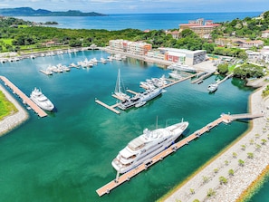 A marina with multiple boats docked, a large cruise ship, and buildings in the background. - Flamingo View Studio 415 (Playa Flamingo)