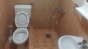 Pieni kylpyhuone, jossa on wc, bidee ja pesuallas.