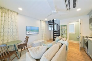 A living room with a sofa, chairs, a table, a TV, a staircase, and a kitchen area. - NEW! Gulfbreeze Guest Cottage, 151 Steps to Seaside Beach Access (Santa Rosa Beach)