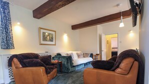 A living room with a sofa, two armchairs, a blue carpet, and a framed picture on the wall. - Linhay Barn (Saltash)
