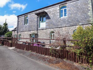 A stone building with multiple windows and a wooden fence. - Linhay Barn (Saltash)