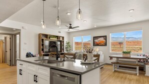 A spacious kitchen with a large island, modern appliances, and a view of the desert landscape. - American Dreams: Prime Location by Pool! (Hurricane)